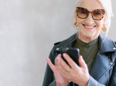 Starsza kobieta w okularach trzyma telefon w dłoni